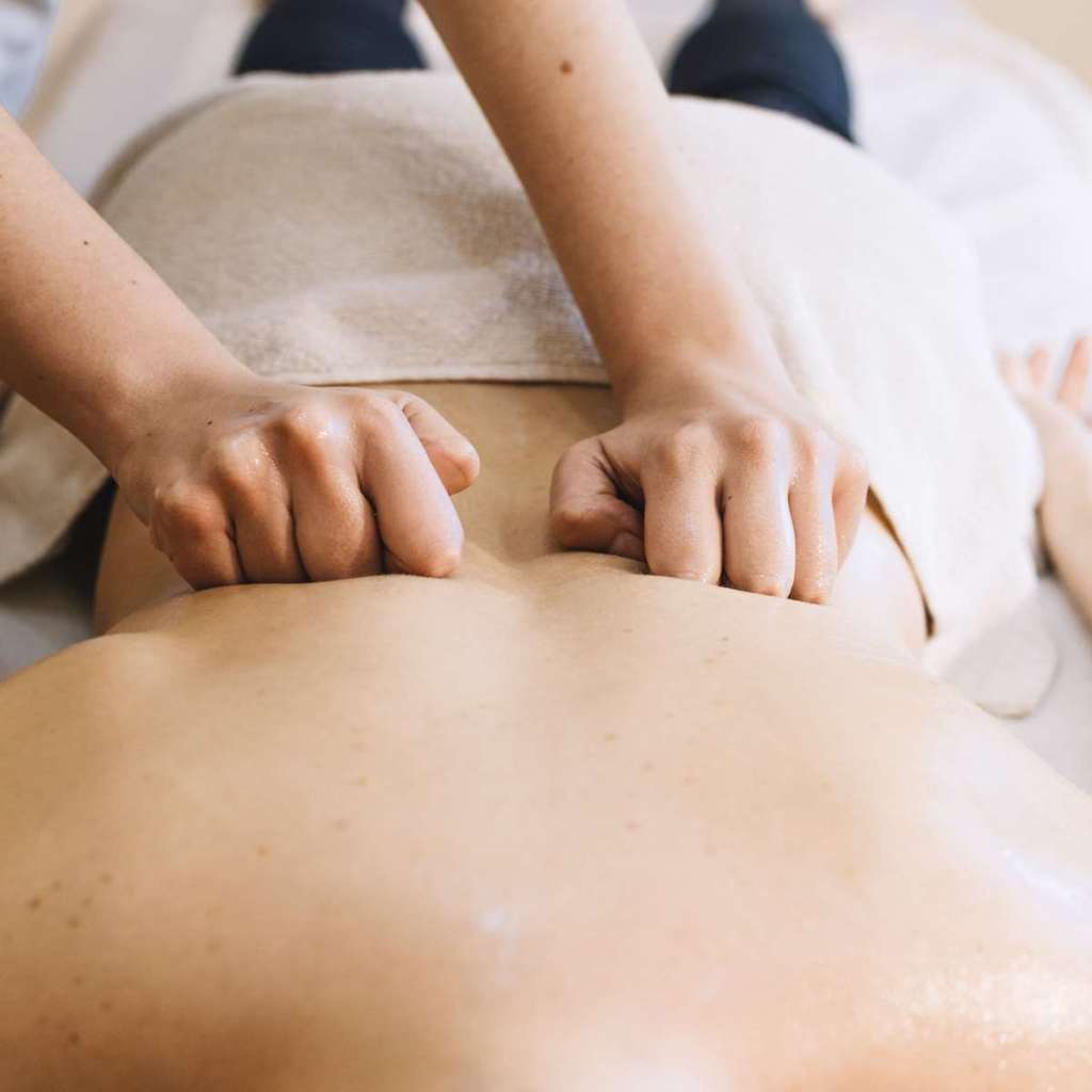 Massage relaxant du dos et des jambes réalisé avec les poings dans une ambiance douce.