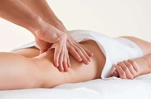 Massage drainant dynamique réalisé sur la cuisse d’une femme adulte.