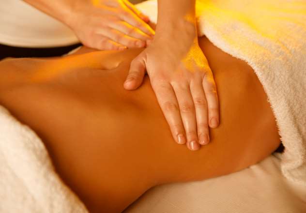Massage drainant ciblant le ventre et le haut des jambes d’une femme adulte.