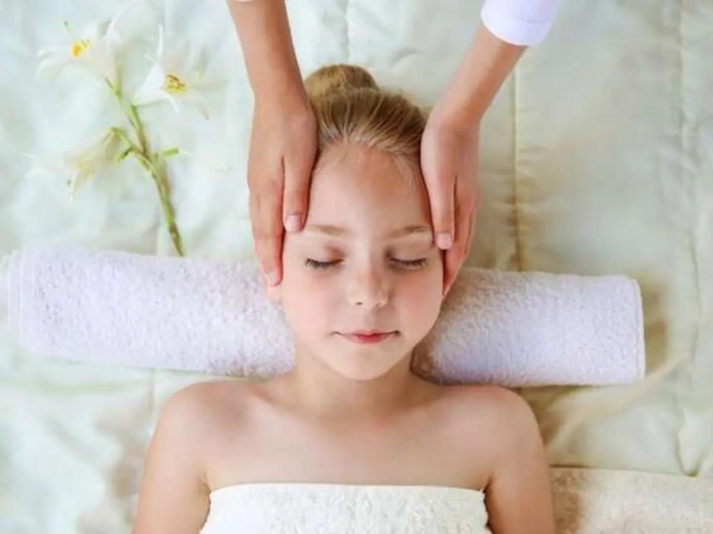 Massage doux du visage et des tempes réalisé sur une enfant.